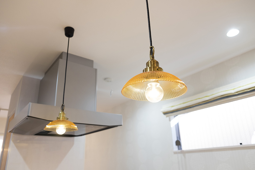 キッチンの腰壁上に吊り下げられているペンダントライト。アンバー色のガラスシェードが雰囲気ある光を放っています。