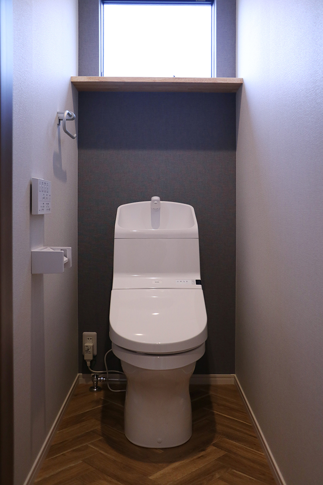 標準仕様の2階トイレ（便器：TOTO HV ／背面クロス：サンゲツ SP9544／クッションフロア：サンゲツ HM-4029／棚：クリア塗装）