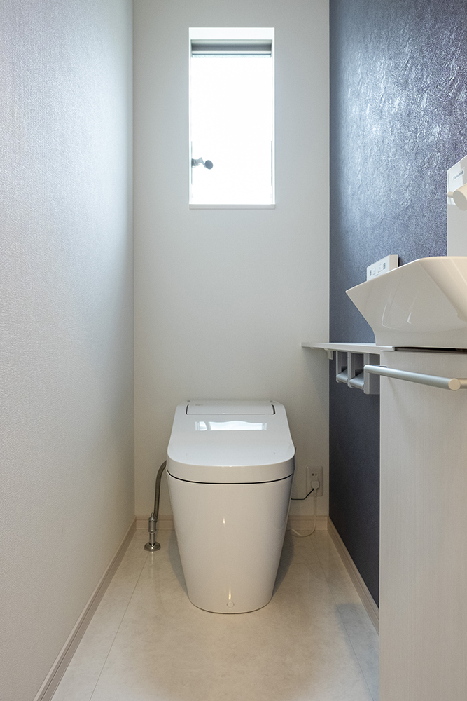 １階標準トイレにはブルーのアクセントクロスを　カウンター：ホワイトオーク柄
