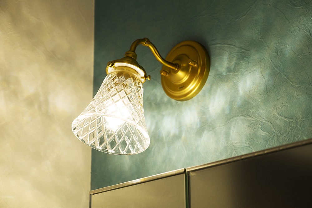 アンティークゴールドのつる首形状アームにカッティングガラスのシェードが素敵な洗面室のブラケット