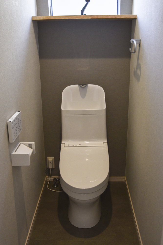 １Fと同じくグレーベースな２Fトイレ（棚：集成材　クリア塗装　トイレ背面アクセントクロス：SLP-838　フロア：HM-4090）