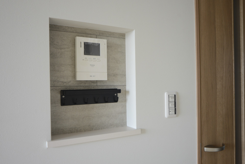 ダイニングにあるニッチ(下枠:DAIKEN hapia ネオホワイト/背面クロス:サンゲツ FE76619/キーフック:ブラック)※202号室